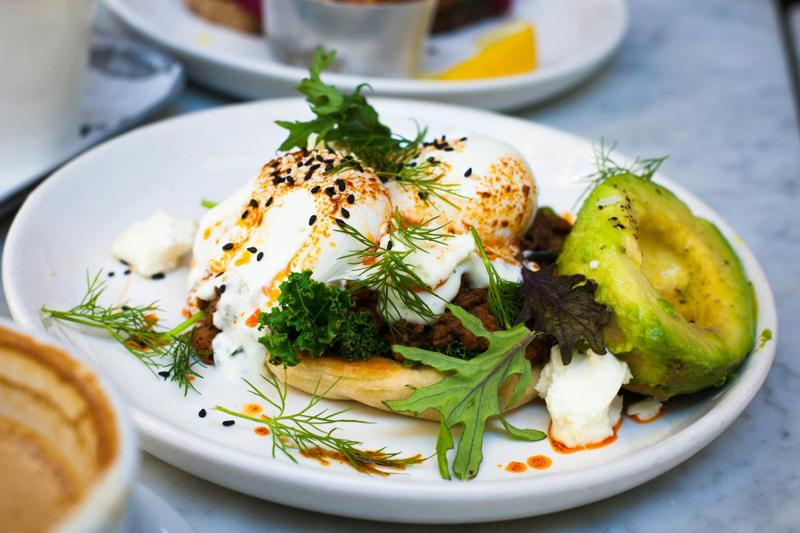 Delicious brunch featuring poached eggs, avocado, and herbs on a plate. Perfect for healthy eating.